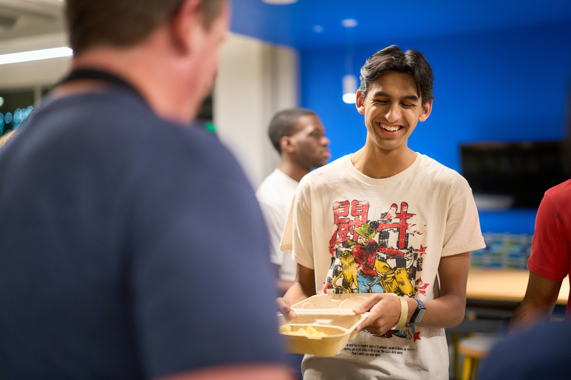 student smiling and holding a plate of food
